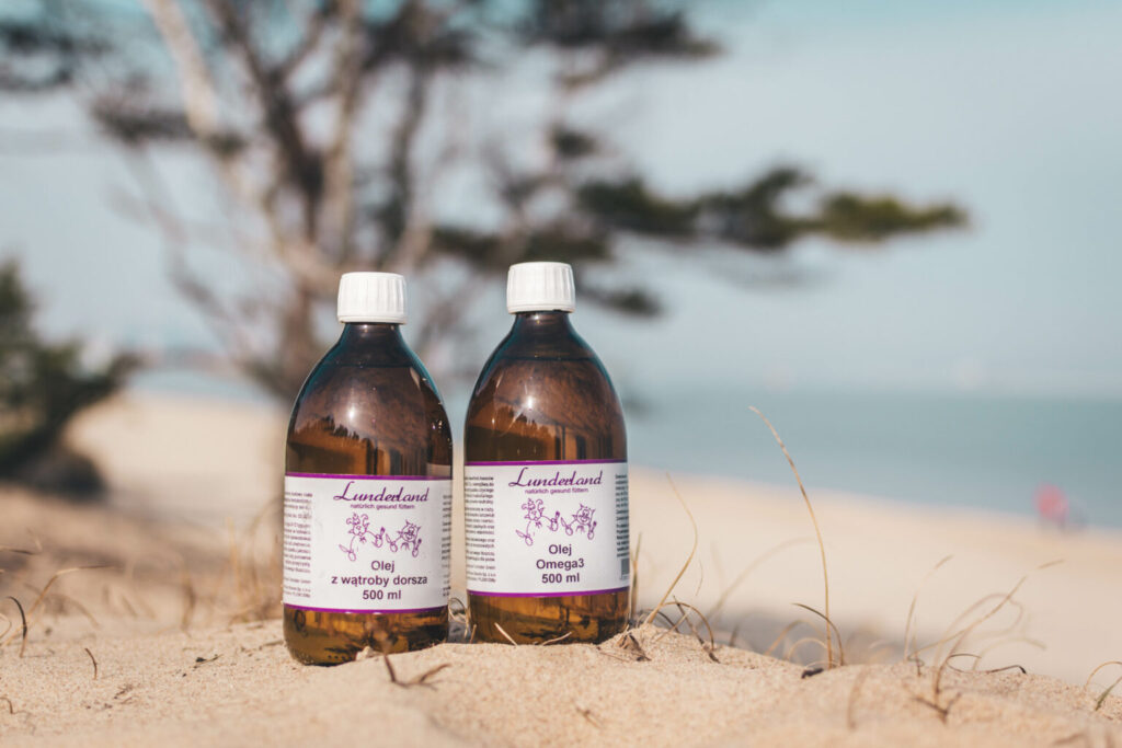 Dwie butelki olejów Lunderland na piasku plażowym.